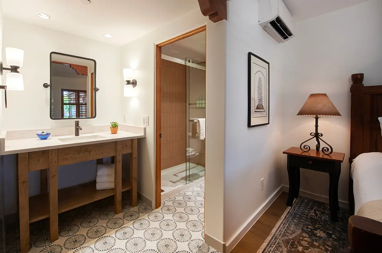 Modern rustic bathroom vanity and tiled floor leading to a glass shower in a Napa Valley hotel suite at Piñon Court.