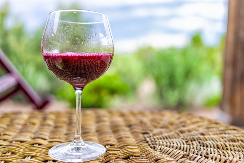 A chilled glass of red wine rests on a woven outdoor table at a Napa Valley hotel.