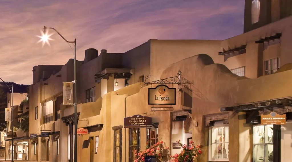 Illuminated adobe-style hotel exterior at dusk featuring storefronts, including a sign for breakfast places in napa.