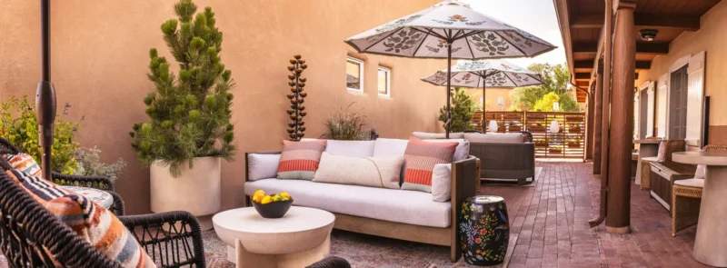 Piñon Court hotel suite patio with comfortable outdoor seating, patterned umbrellas, and brick paving, ideal for Napa Valley hotels.