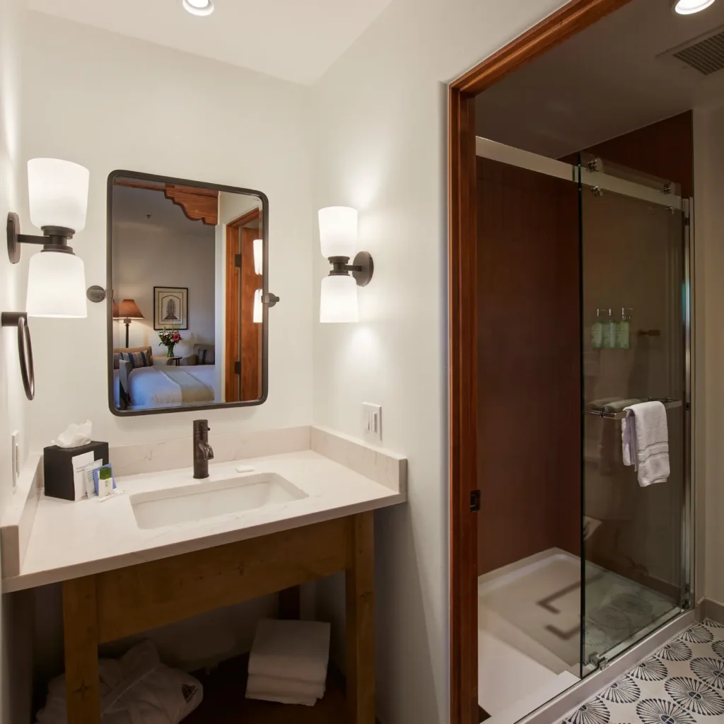 Contemporary hotel bathroom with a wood vanity, walk-in glass shower, and patterned floor tiles at a Napa Valley hotel.