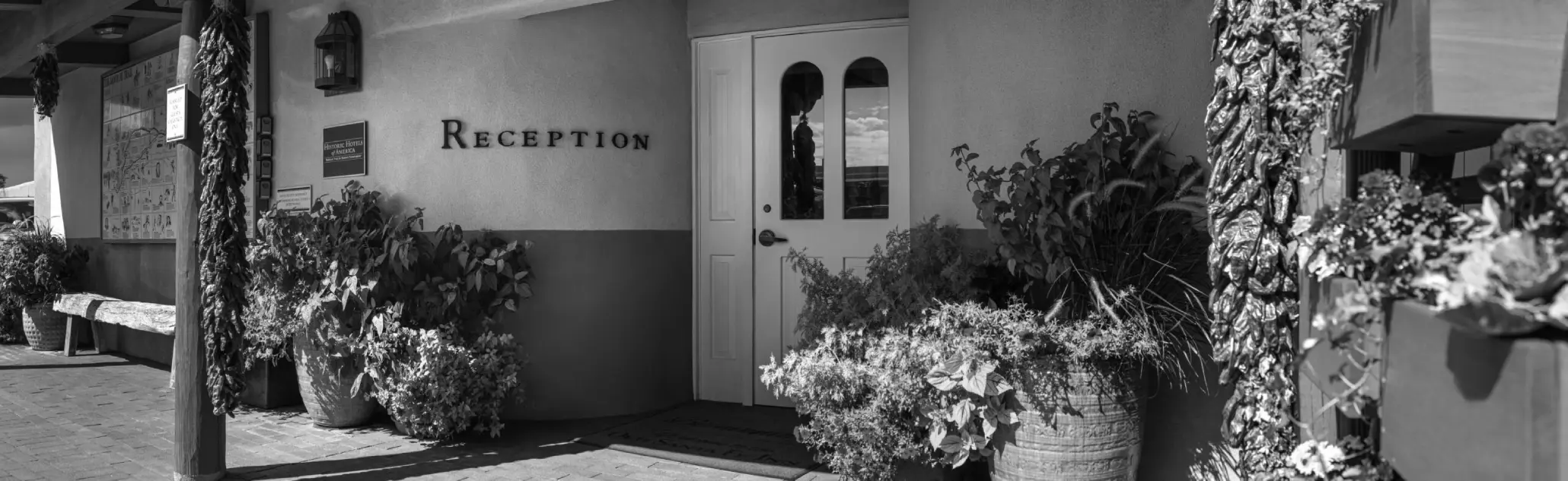 The reception entrance of the napa valley hotel features a white door, large planters, and southwestern-style decor.