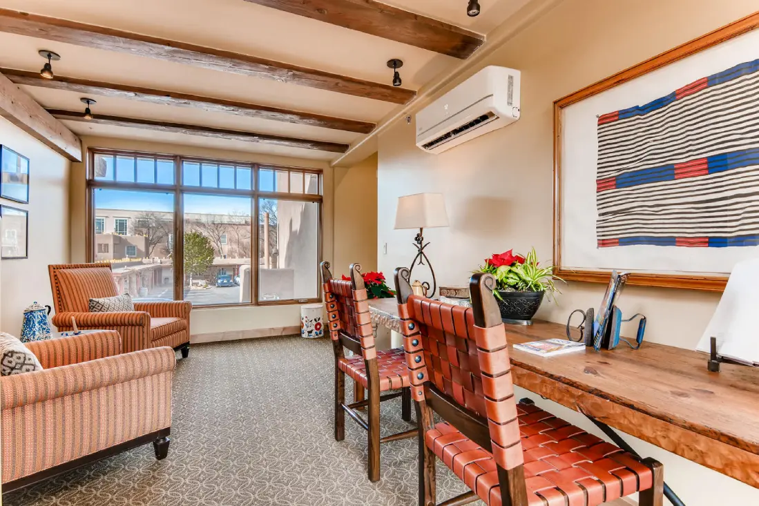 Cozy hotel lounge featuring exposed wood beams, woven leather seating, and large windows overlooking the property.
