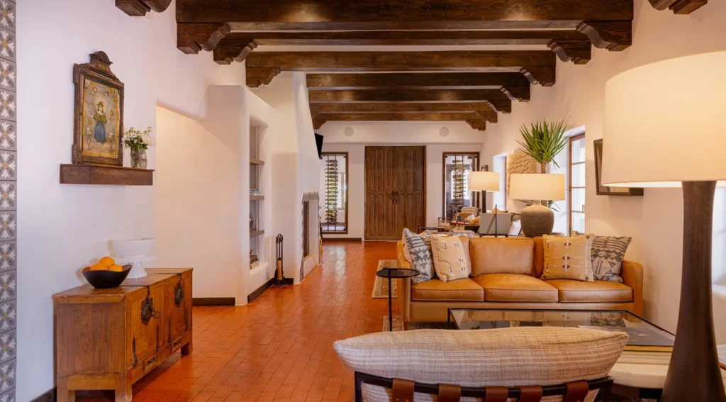 Warm interior of a Napa Valley hotel and suites featuring exposed wood beams, brick floors, and a luxurious leather sofa.
