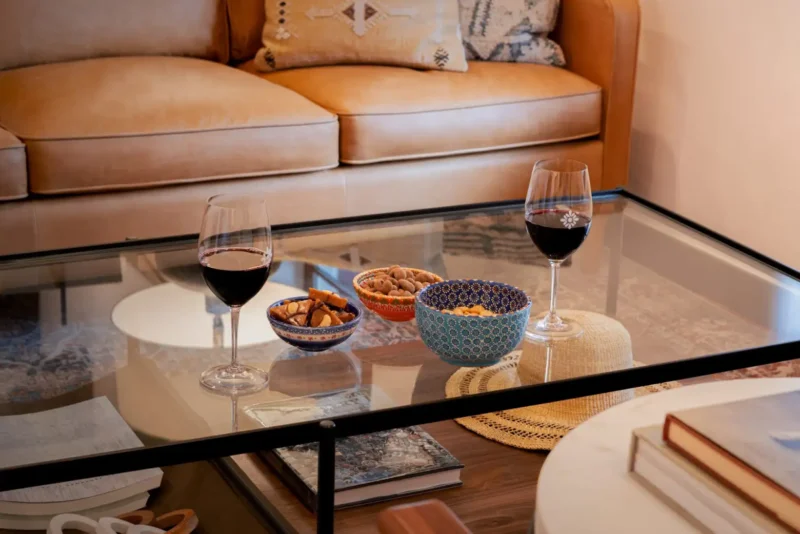 Red wine and snacks on a glass coffee table in a comfortable living space inside a Napa Valley hotel.