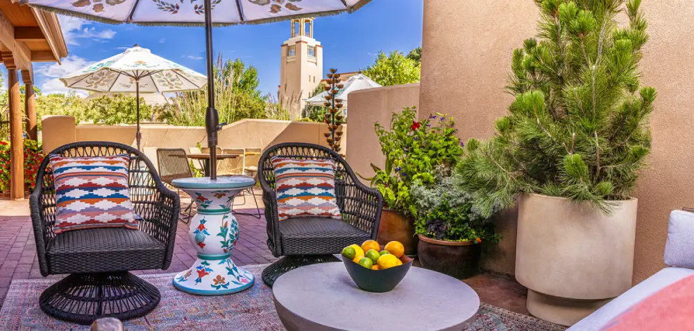 Cozy outdoor lounge patio with wicker chairs, citrus fruit, and an umbrella, representative of hotels in Santa Fe, NM.