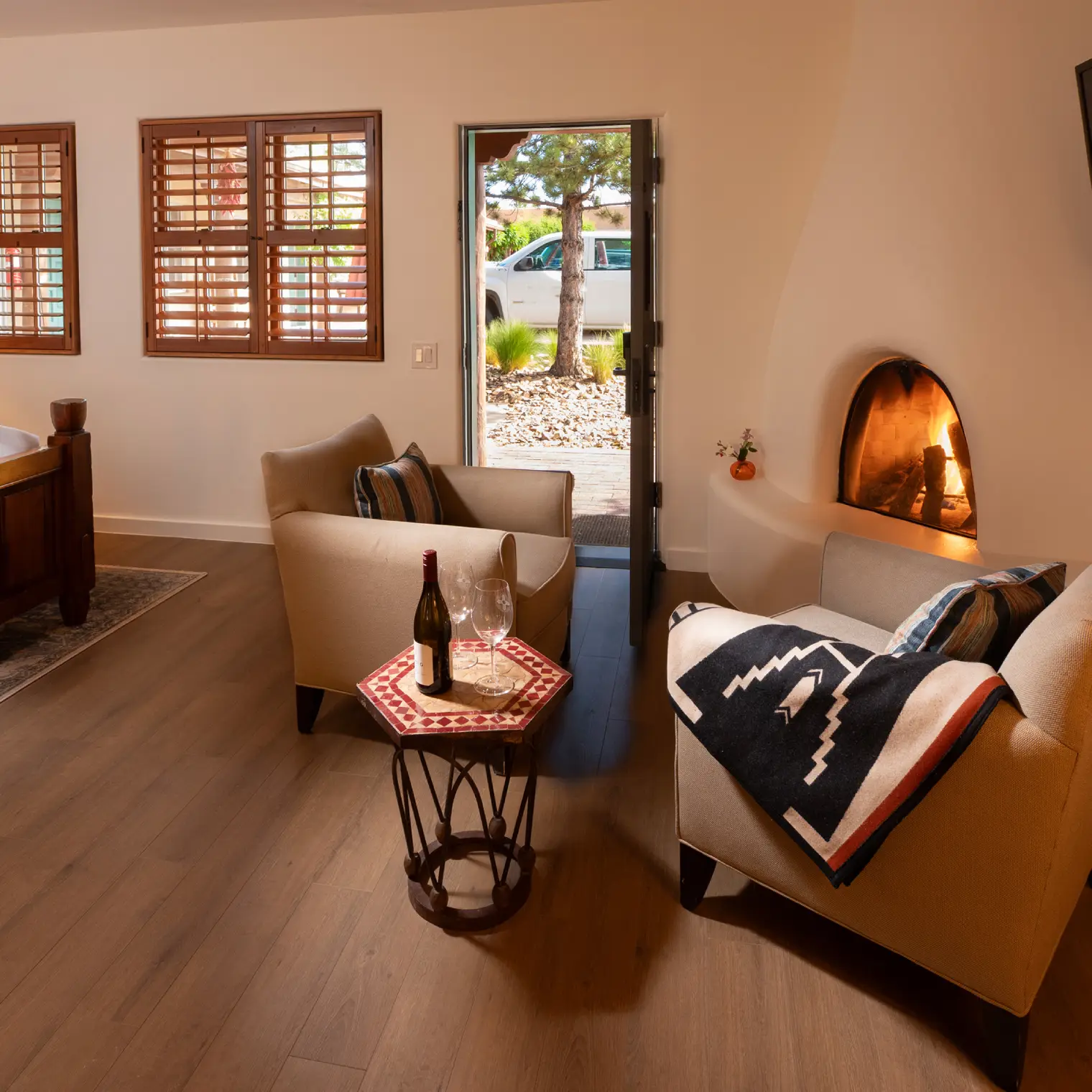 Cozy Piñon Court Santa Fe, NM hotel suite featuring a lit fireplace, wood shutters, and a wine service setup.