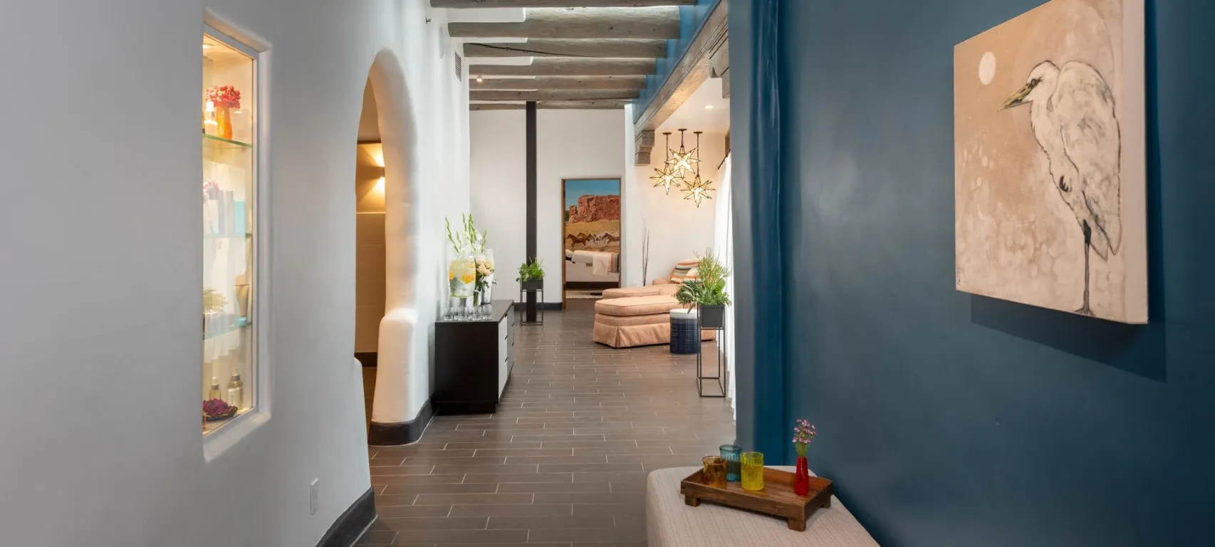 A brightly lit lobby with a modern aesthetic, featuring a chandelier, plants, and artwork.
